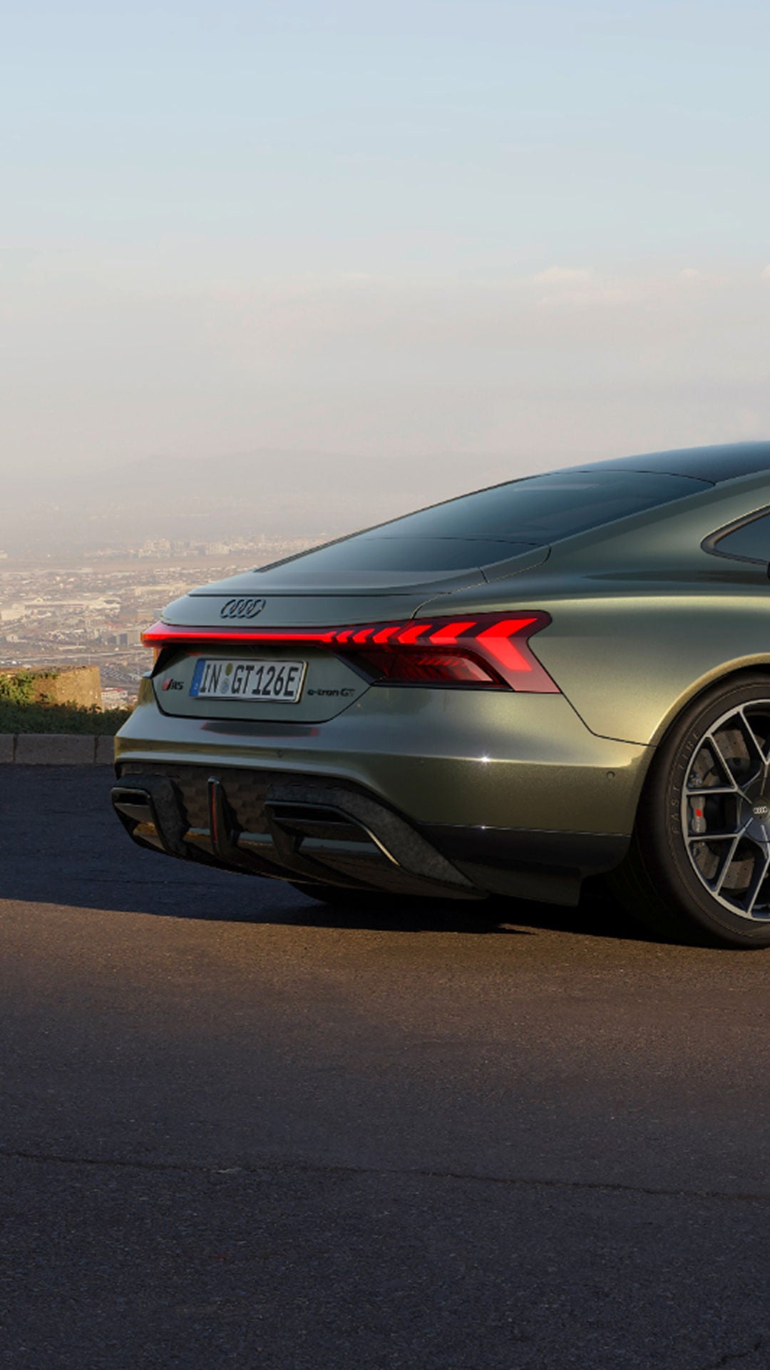 A green Audi electric sedan parked with a cityscape in the background. 