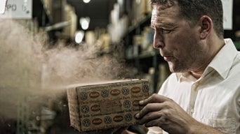 Mann bläst in einer Werkstatt Staub von einem Audi Paket