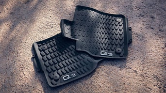 Zwei schwarze Q3 Allwetter-Fußmatten auf Betonboden.