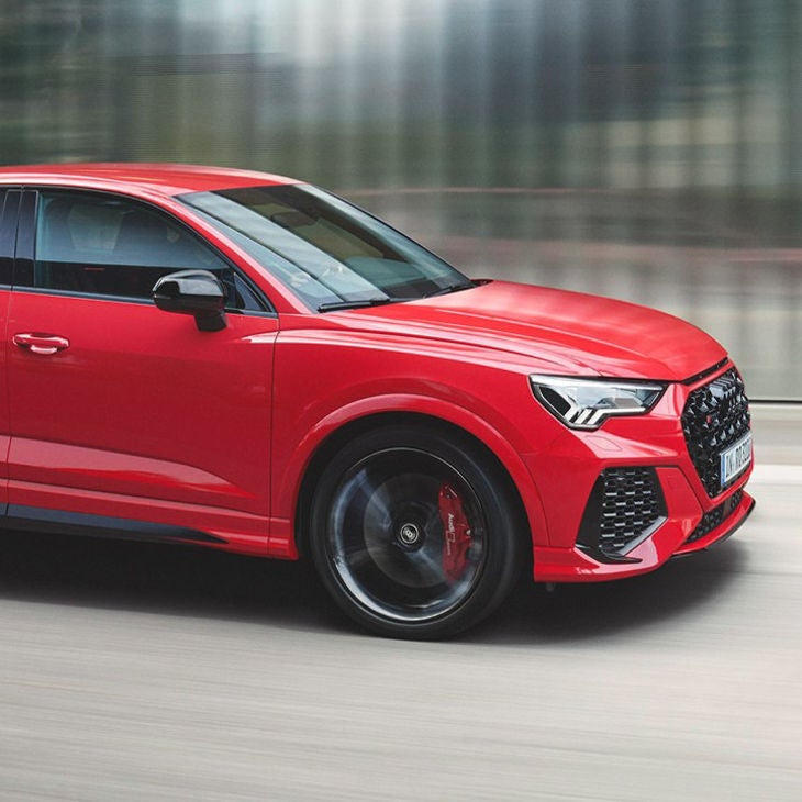 A red car in motion with blurred background indicating speed.