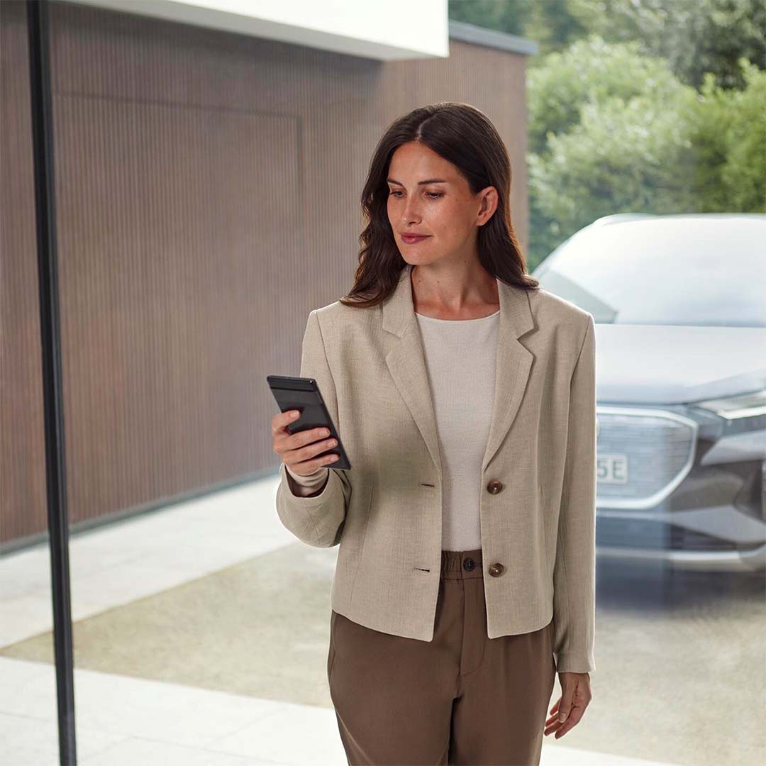 Dame ser på mobilen. Audi i bakgrunnen.