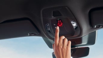 Der Zeigefinger einer Frauenhand betätigt die SOS Notruftaste.