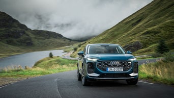 An Audi Q3 Sportback in Malpelo Blue Metallic drives along a country road in the middle of a mountain landscape.