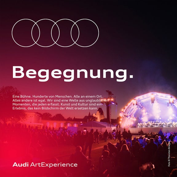 Abendliches Open-Air-Konzert mit Publikum vor beleuchteter Bühne; Audi ArtExperience und Text „Begegnung“.