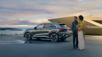 A woman and a man stand behind an Audi Q5 model