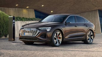 A brown Audi electric vehicle charging at a charging station