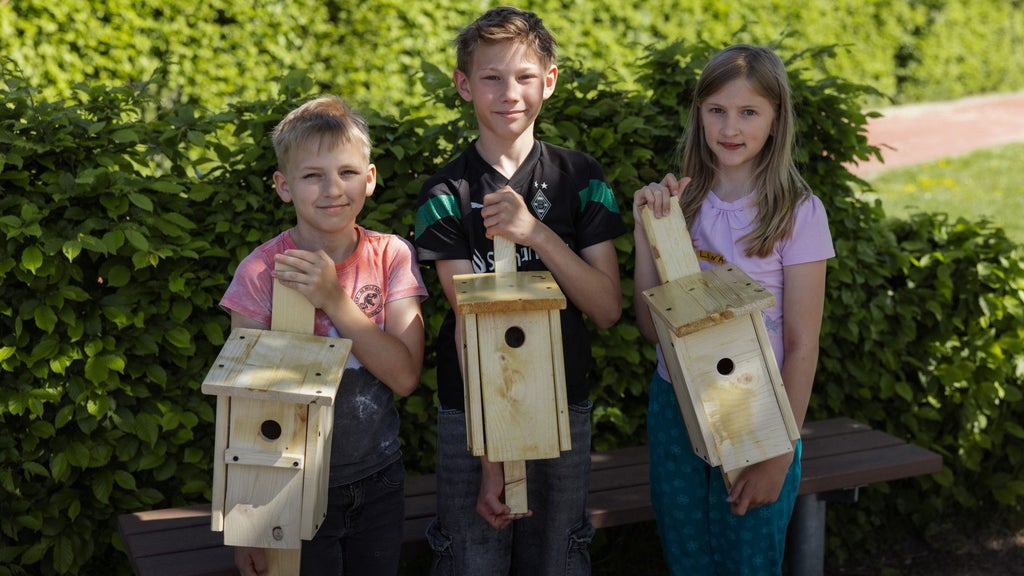 Drei Kinder mit selbstgebauten Vogelhäuschen.