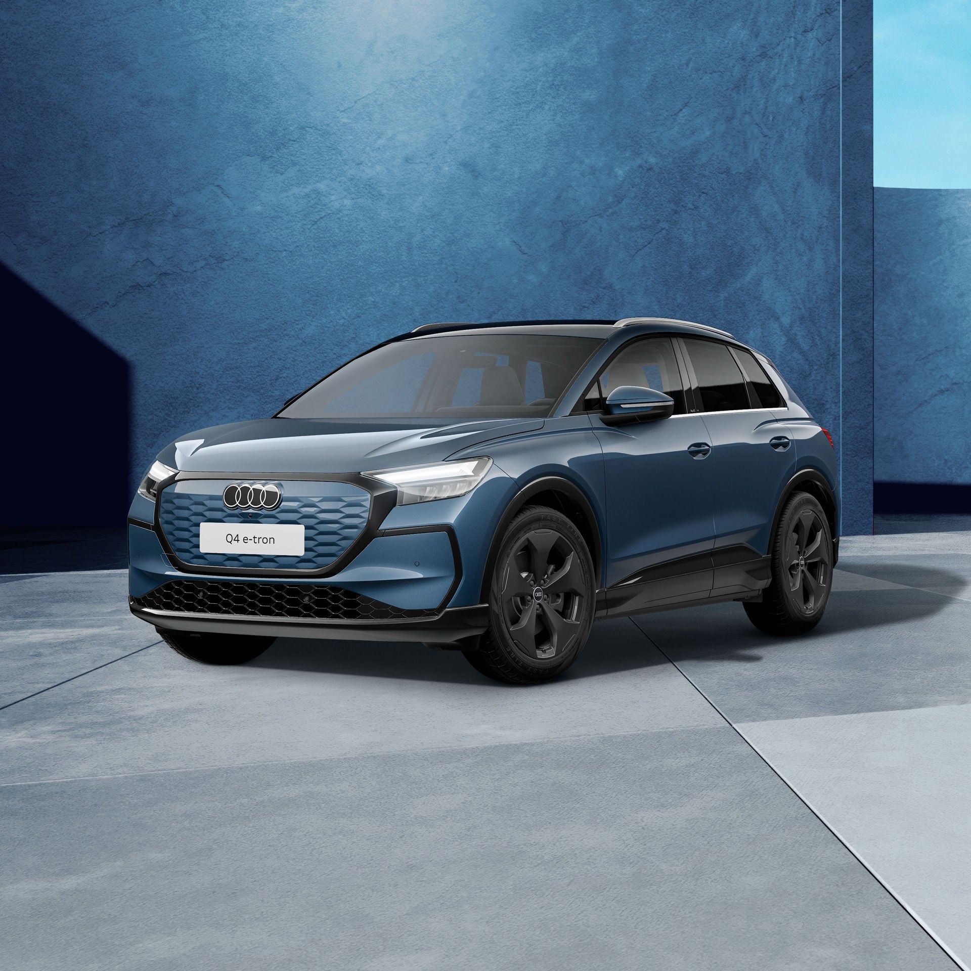 Ein plasmablau metallischer Audi Q4 SUV e-tron von schräg vorne fotografiert vor einer modernen Kulisse.