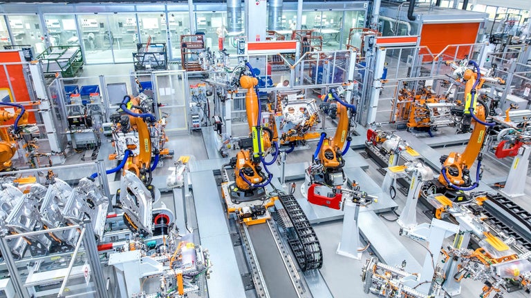 Industrielle Roboterarme in einer automatisierten Fertigungslinie montieren Fahrzeugkomponenten.