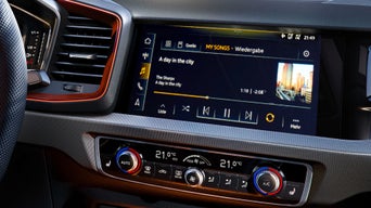 Infotainment-Display im Audi mit Musikwiedergabe „A day in the city“ und Bedienelementen für die Klimaanlage.