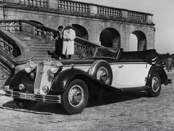 Schwarz-weiß-Aufnahme von einem Paar auf einer Steintreppe. Im Vordergrund steht ein Horch 853