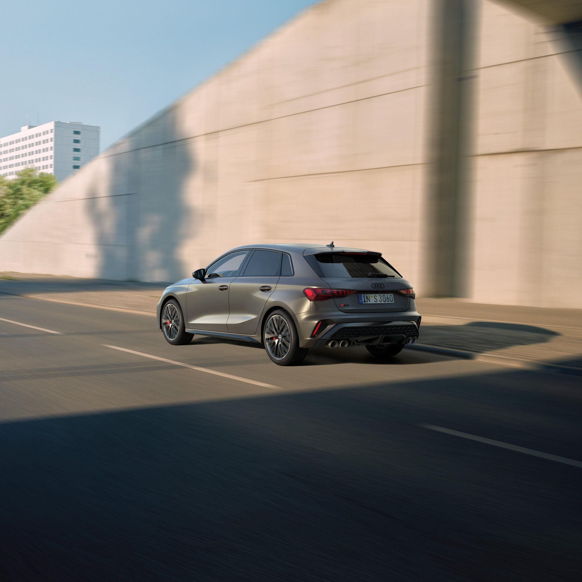Ein grauer Audi S3 Sportback fährt aus einem Tunnel heraus bei blauem Himmel. Das Auto wird aus dem Tunnel heraus fotografiert.