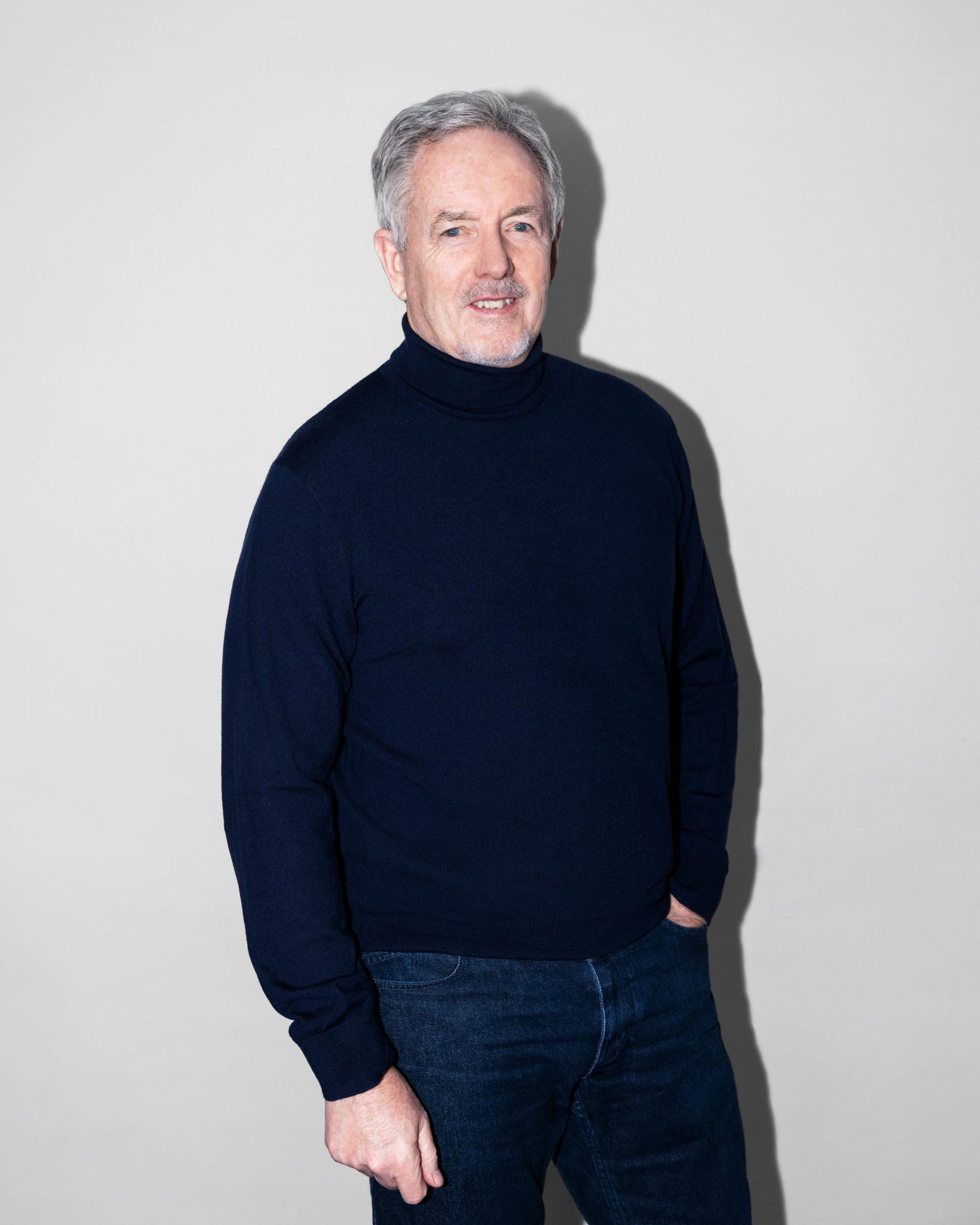 Portrait von Trevor Hill, der vor einer weißen Wand steht.