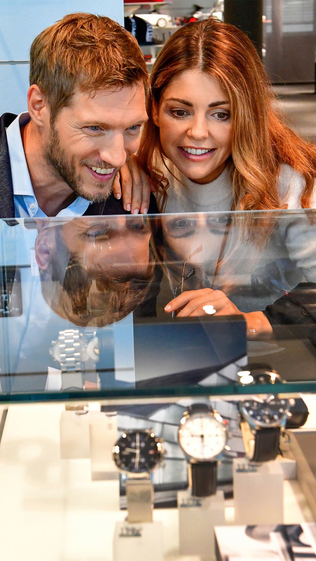 Man and woman look into a display case, next to a man in sunglasses and a leather jacket.  