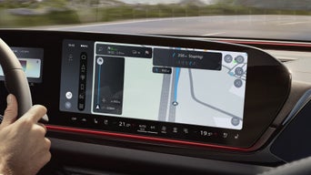 Frau blickt auf das digitale Navigationsdisplay im Audi-Lenkrad mit eingeblendeter Straßenkarte.