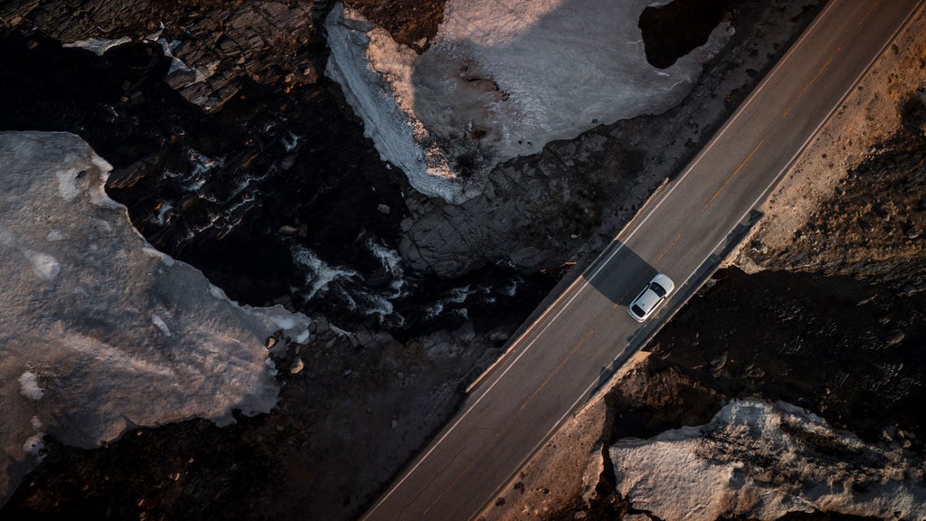 Aerial view of the white Audi A6 Sportback e-tron on a bridge between rocky gorges.