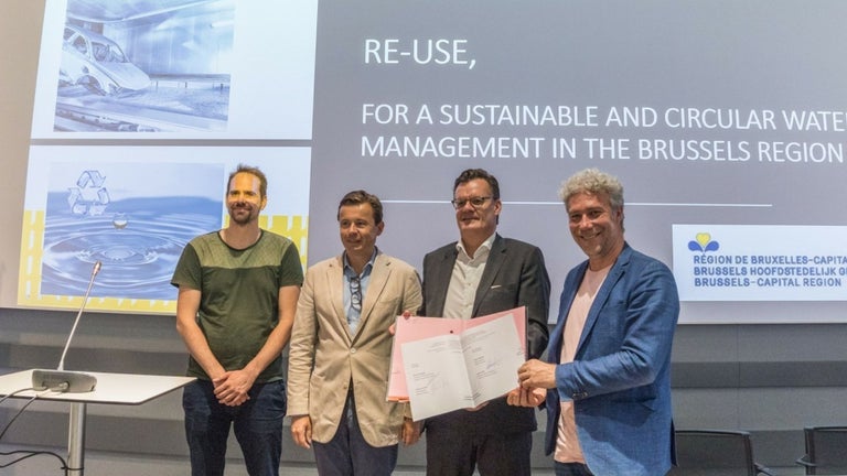 Four men on stage at the presentation of the Re-Use project