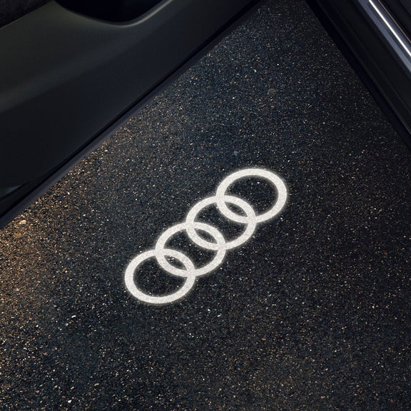 La Audi Q3 Sportback con attenzione sulla portiera aperta e sull’illuminazione LED d’ingresso, che proietta gli anelli Audi sul terreno.