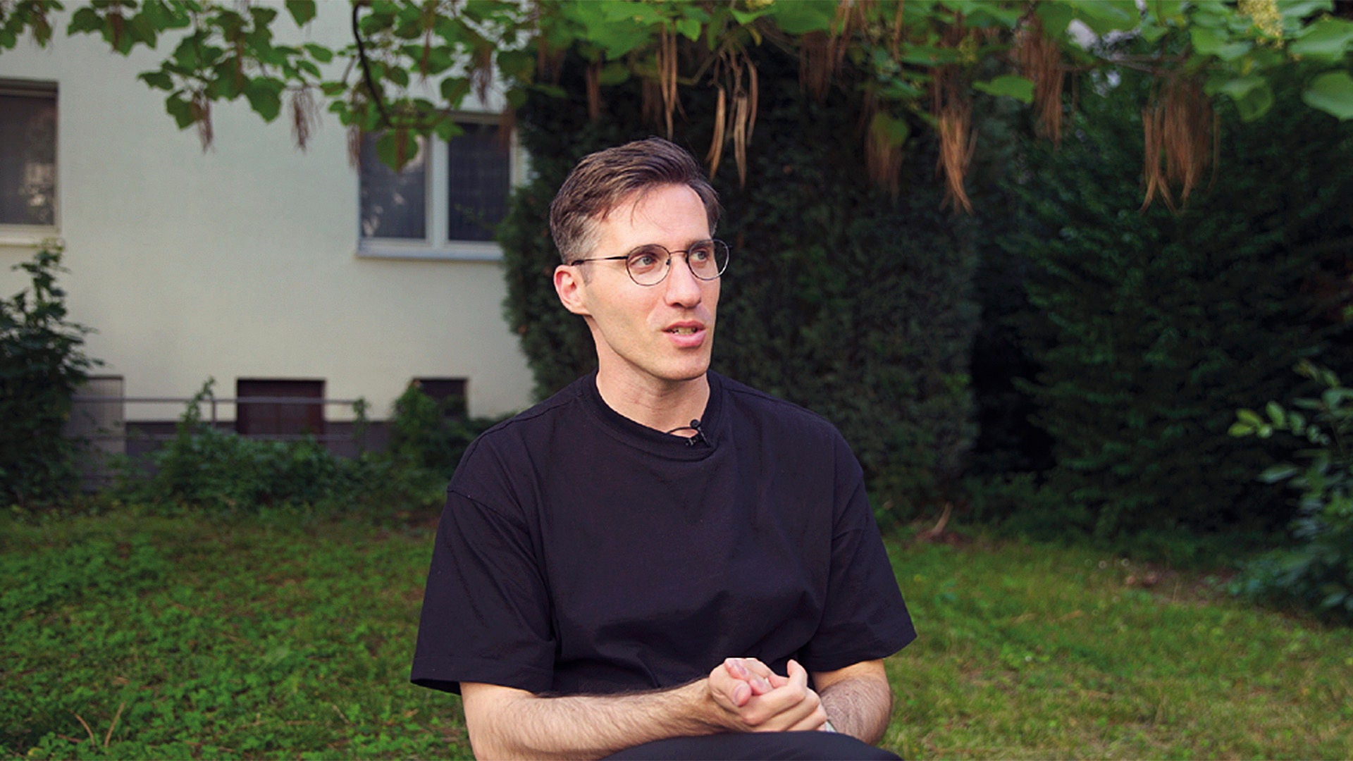 Ein junger Mann sitzt im Garten und erzählt von seinem Leben.