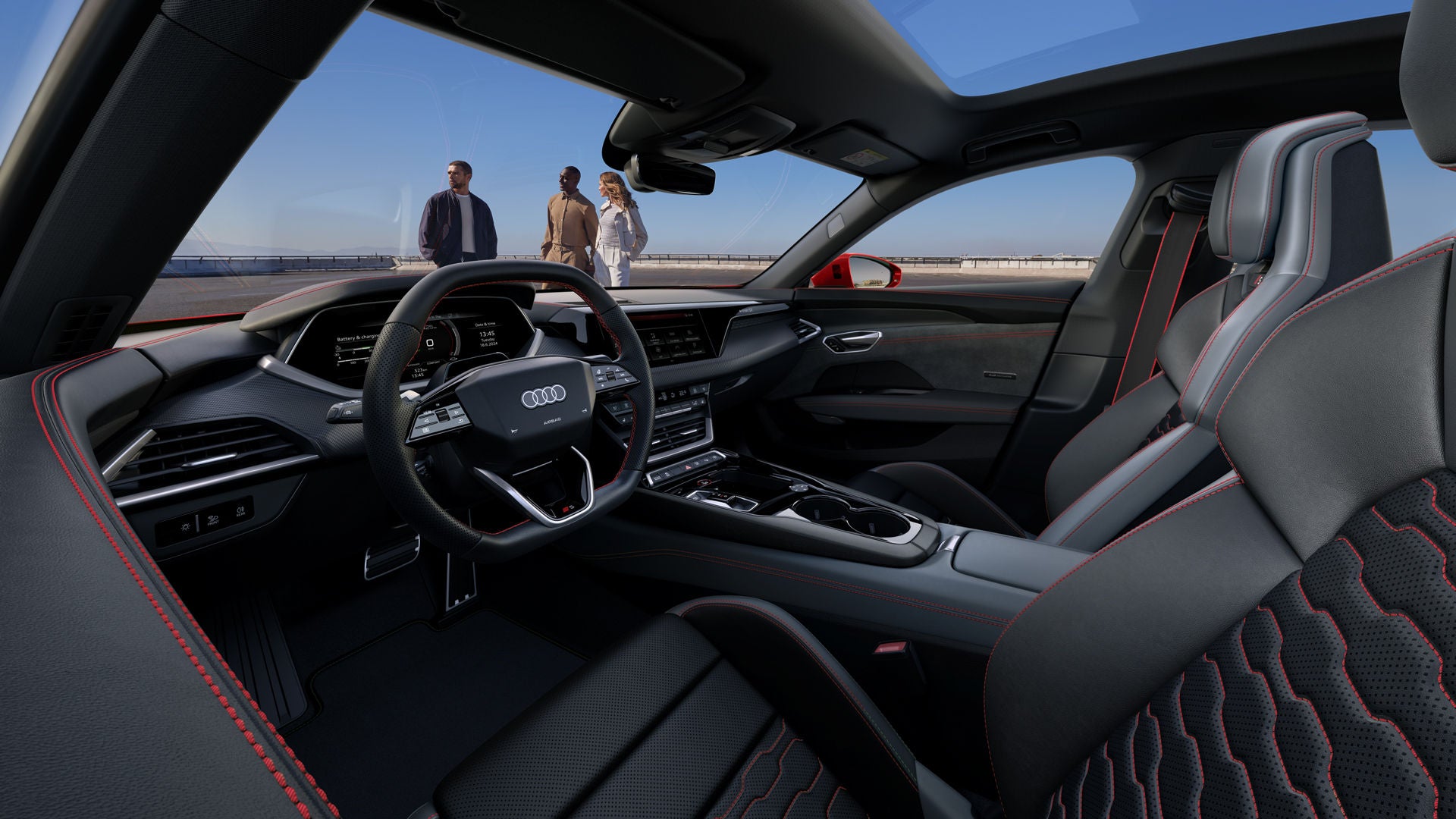 Het interieur van de Audi S e-tron GT, met zwarte sportstoelen met rode stiksels, een glazen panoramisch dak en een zicht op drie mensen die buiten aan de kant van de weg staan.