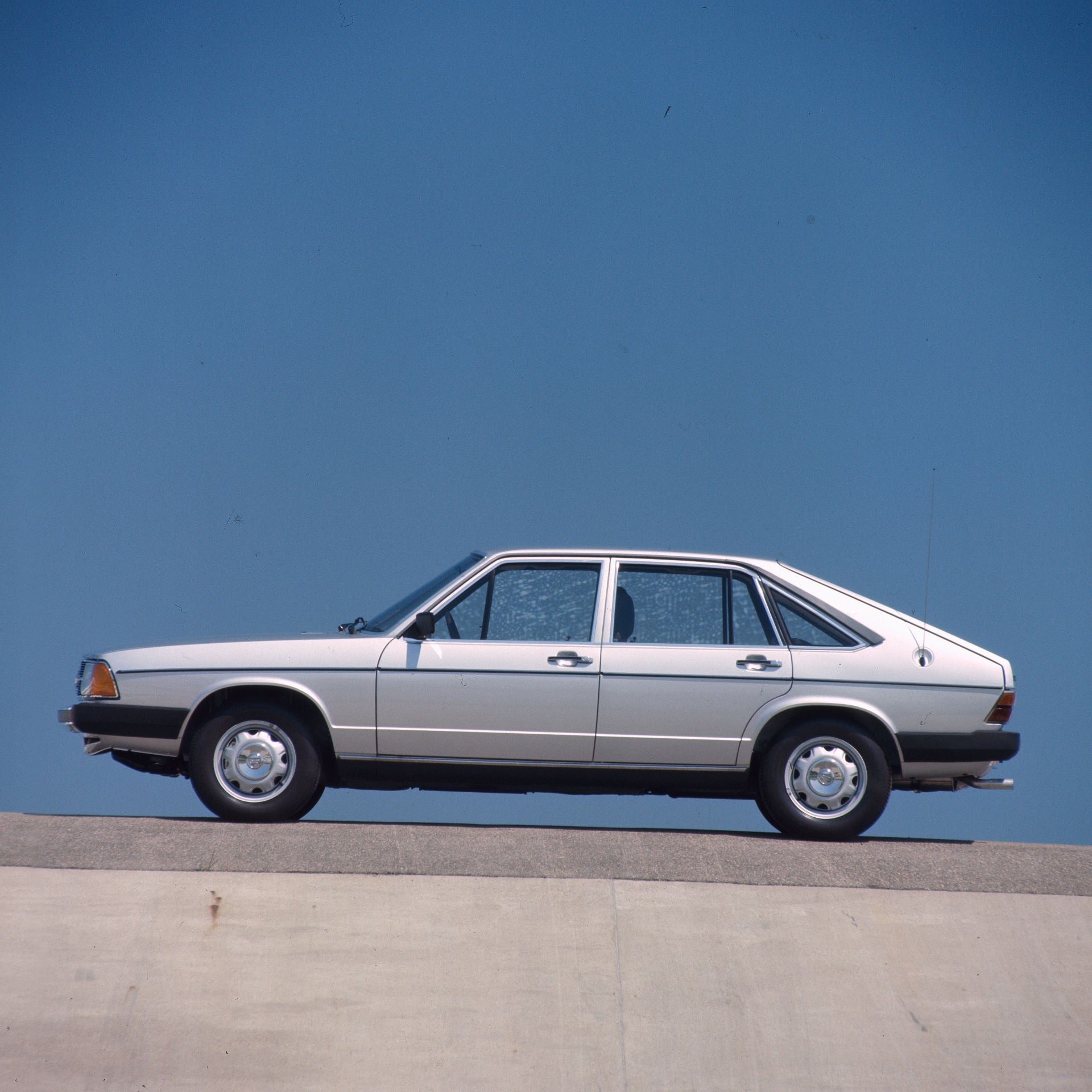 Silberfarbene Limousine der 1970er-Jahre in Seitenansicht vor blauem Hintergrund