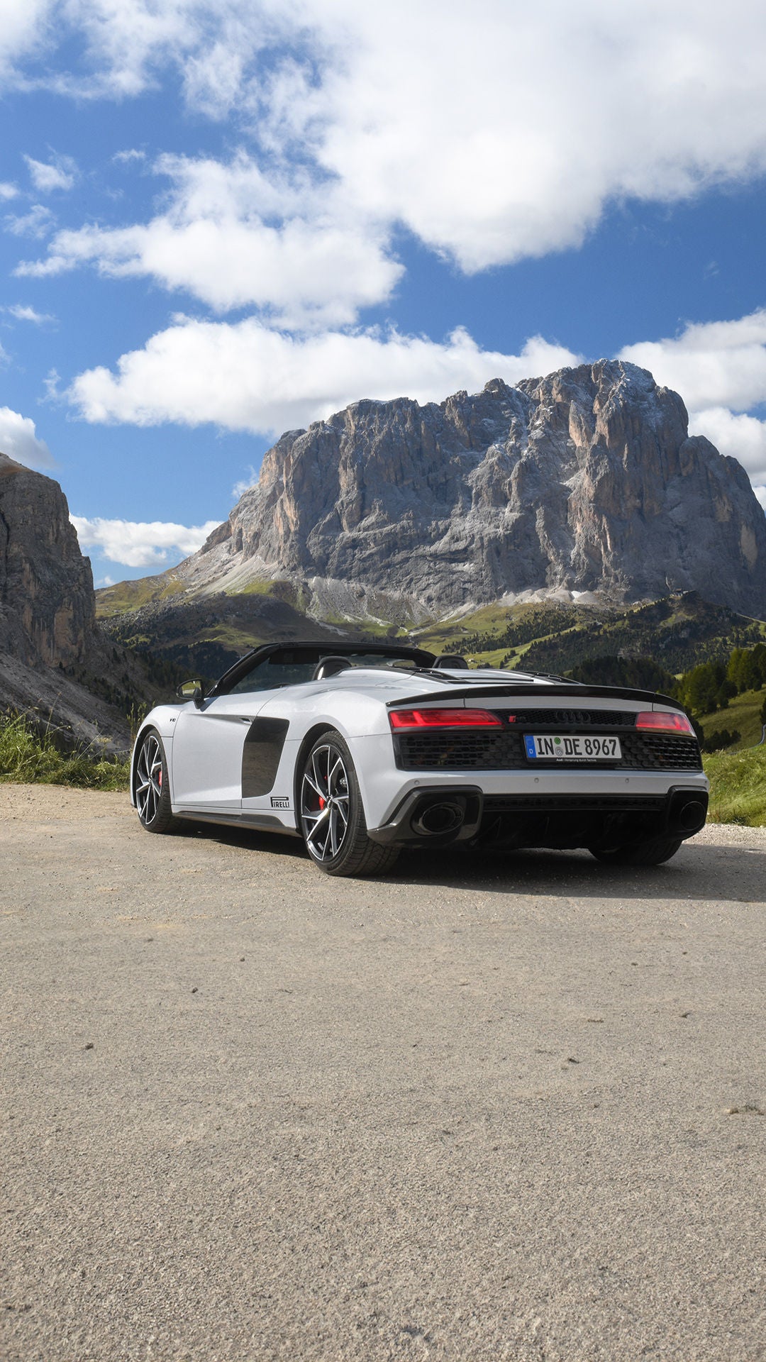 White Audi R8 Spyder V10 performance quattro with open top (rear view) standing in the mountains in great weather