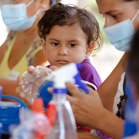 Frauen bauen gemeindam Solarlichtlaternen zusammen. Ein kleines Kind beobachtet sie dabei.
