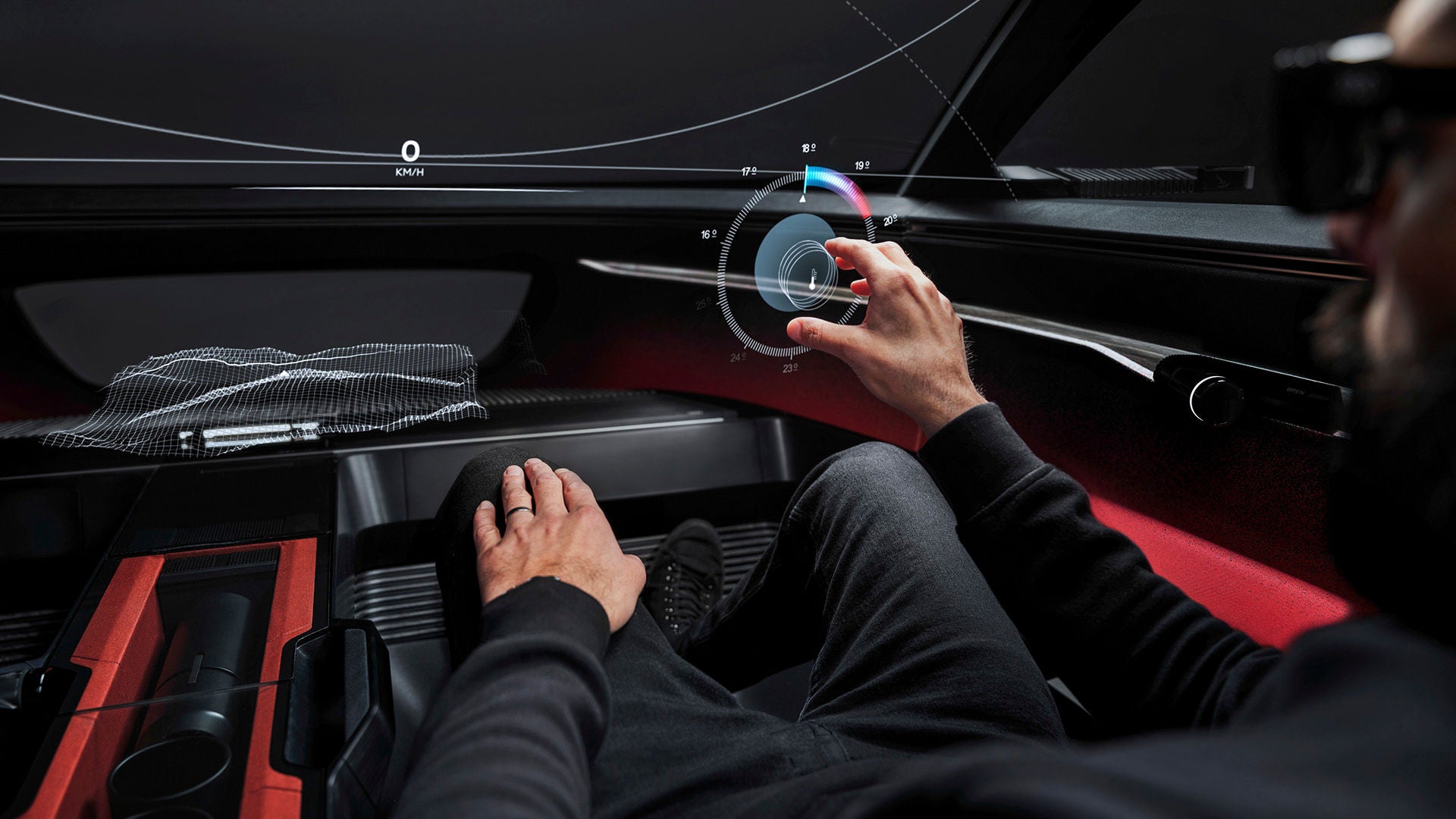 Ein futuristisches Fahrzeug-Cockpit ohne physische Bedienelemente. Eine Hand des Fahrers greift nach einem virtuellen Knopf, der als Hologramm frei in der Luft schwebt. 