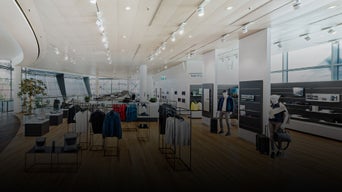 Heller Verkaufsraum mit Kleidung auf Ständern, Anprobekabinen und Verkaufstresen.