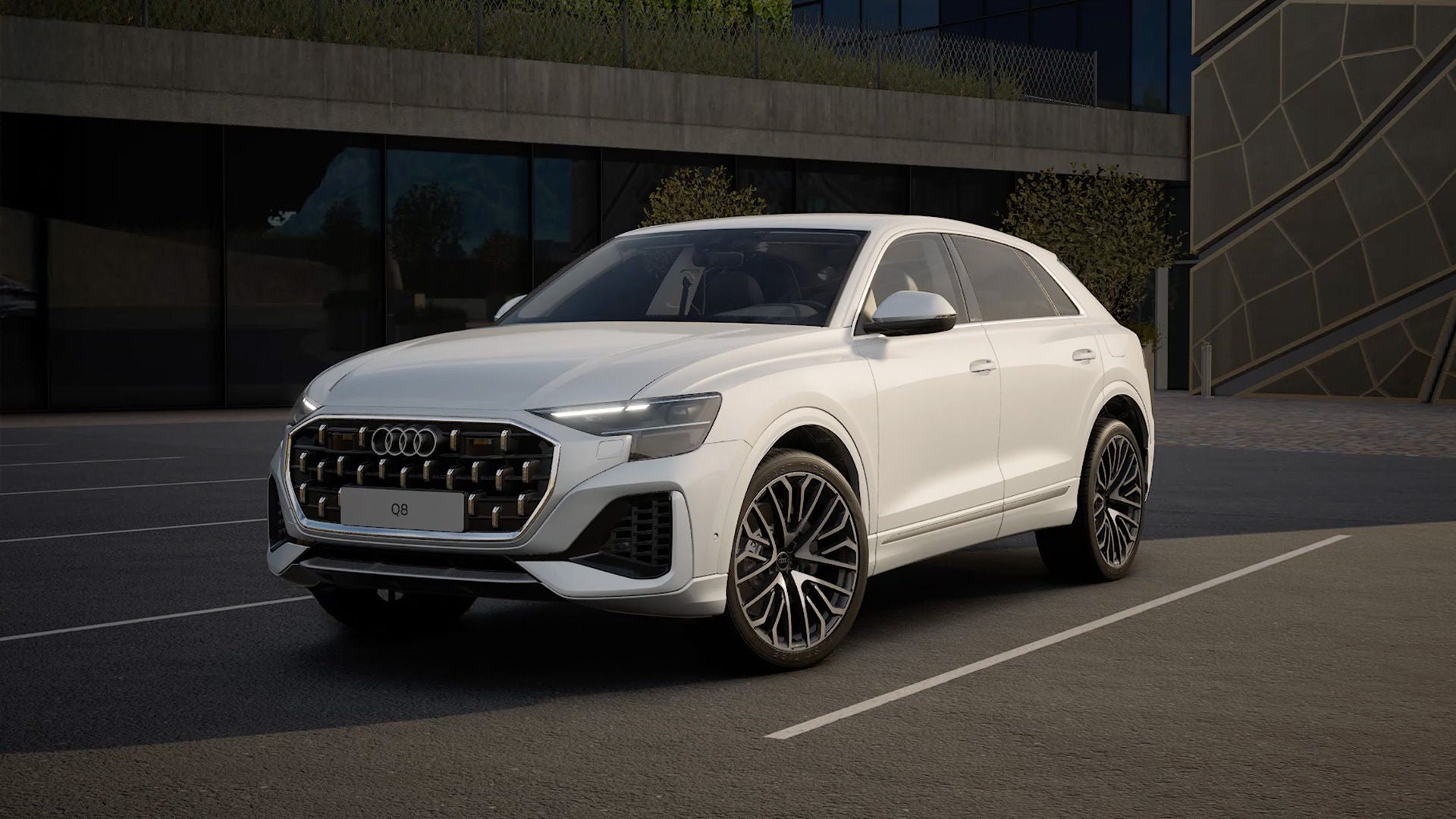 Weißer Audi Q8 SUV steht auf einem Parkplatz vor moderner Architektur, schräg von vorn aufgenommen.