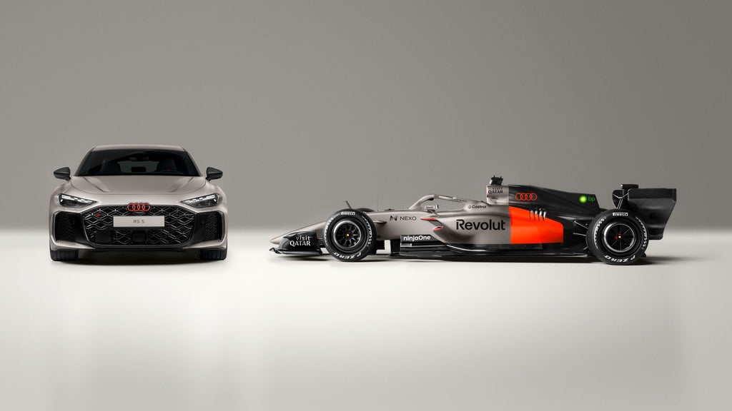 Der Audi RS 5 und der Audi R26 Rennwagen des Audi Revolut F1® Team stehen Seite an Seite. Der Audi RS 5 ist von vorne, der Audi R26 von der Seite zu sehen.