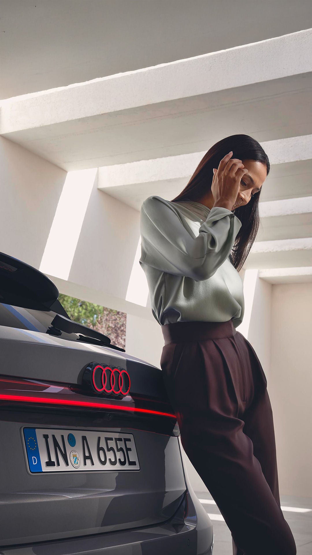 Mann steht vor einem weißen Audi A3 und schaut seitlich an der Kamera vorbei