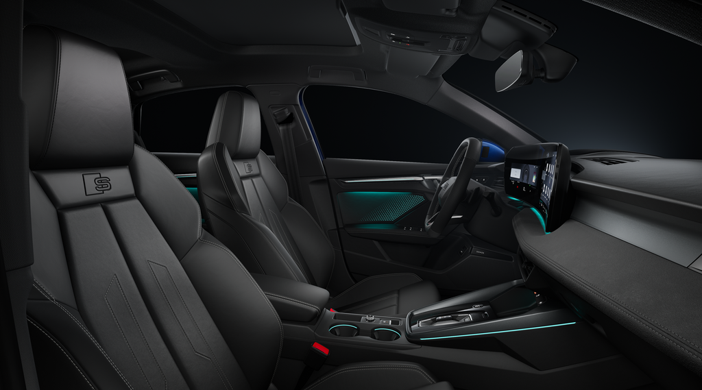 Blick durch das Beifahrerfenster auf die Sportsitze, das Cockpit mit Sportlederlenkrad, Mittelkonsole, digitale Displays und das Ambiente-Licht.