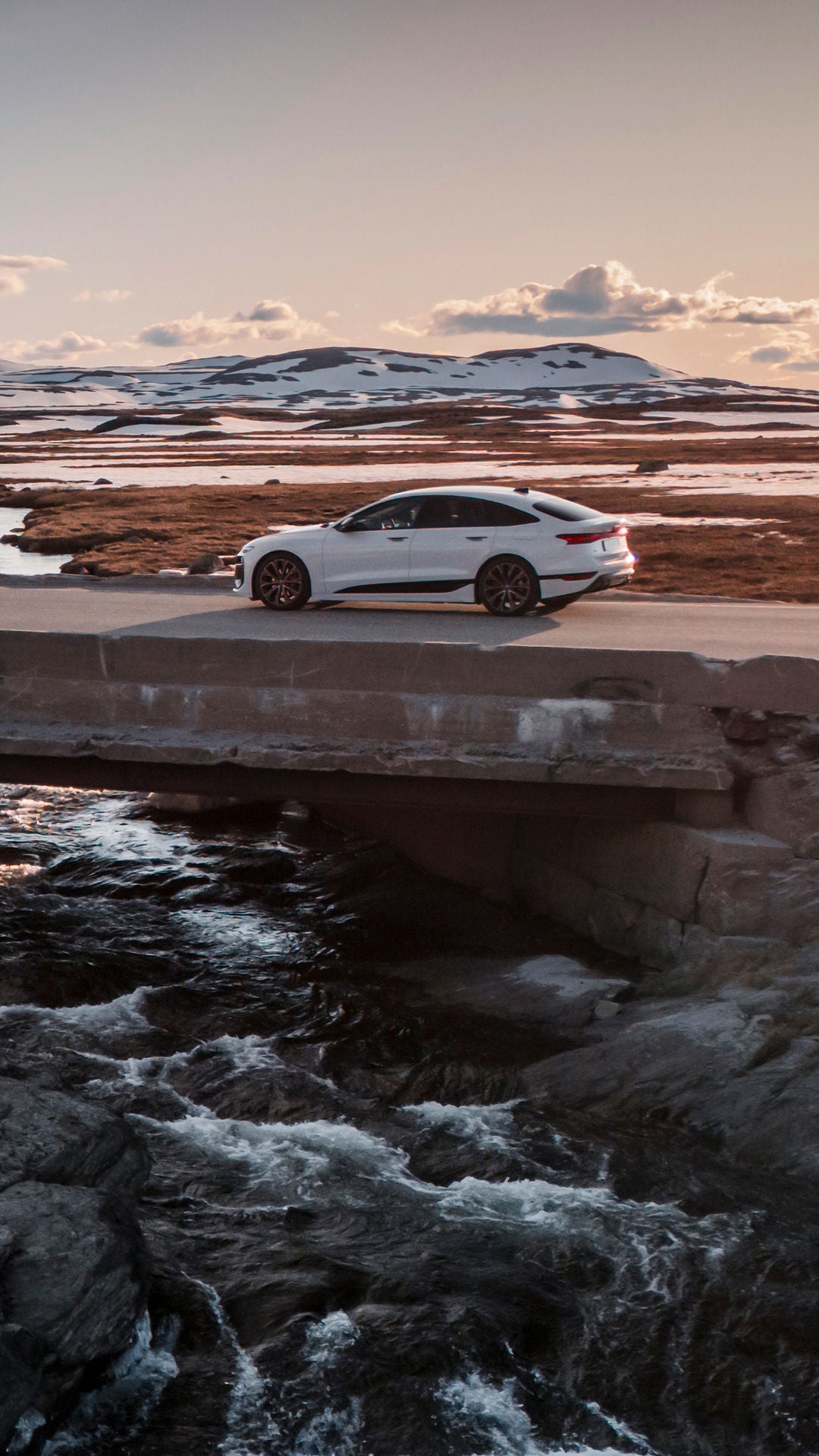 Weite Landschaft, lange Straße mit weißem Audi A6 Sportback e-tron, konzipiert um lange Strecken zurück zu legen.