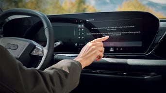 Eine Frauenhand mit ausgestrecktem Zeigefinger betätigt das Entertainment System.