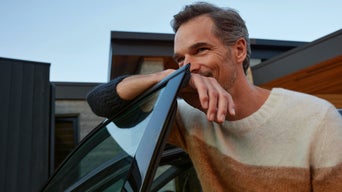 Ein Mann lehnt an einer Autotür