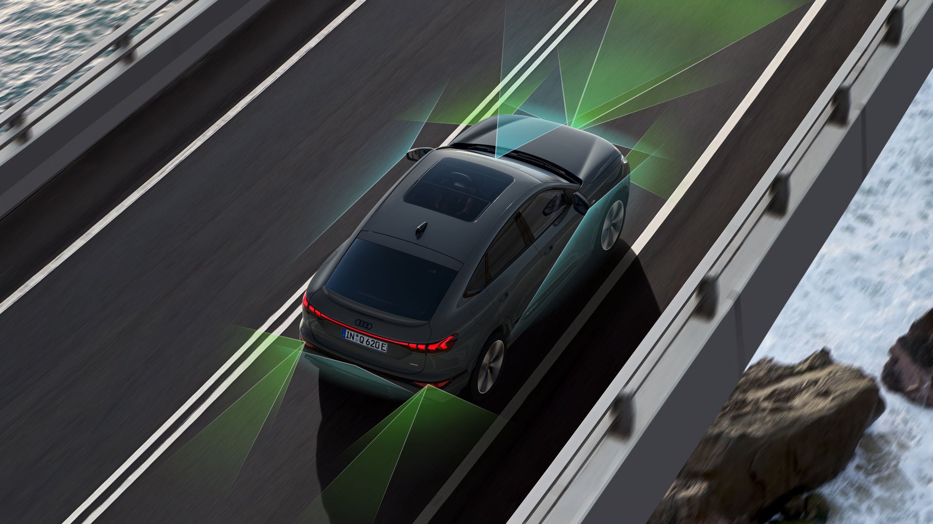 Vogelperspektive eines Audi Q6 e-tron, der über eine Brücke fährt. Unter ihm sind Wasser und Felsen. Um den Q6 herum sind grafisch Sensoren angedeutet, die die Fahrerassistenzsysteme symbolisieren.
