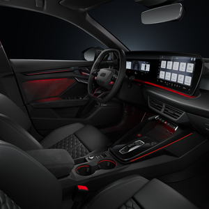 Zicht vanaf de passagierszijde op de cockpit, met het sportieve stuurwiel, de middenconsole, digitale displays en sfeerverlichting.
