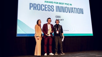 Three people on stage at the Venture Clienting Awards in front of a screen.