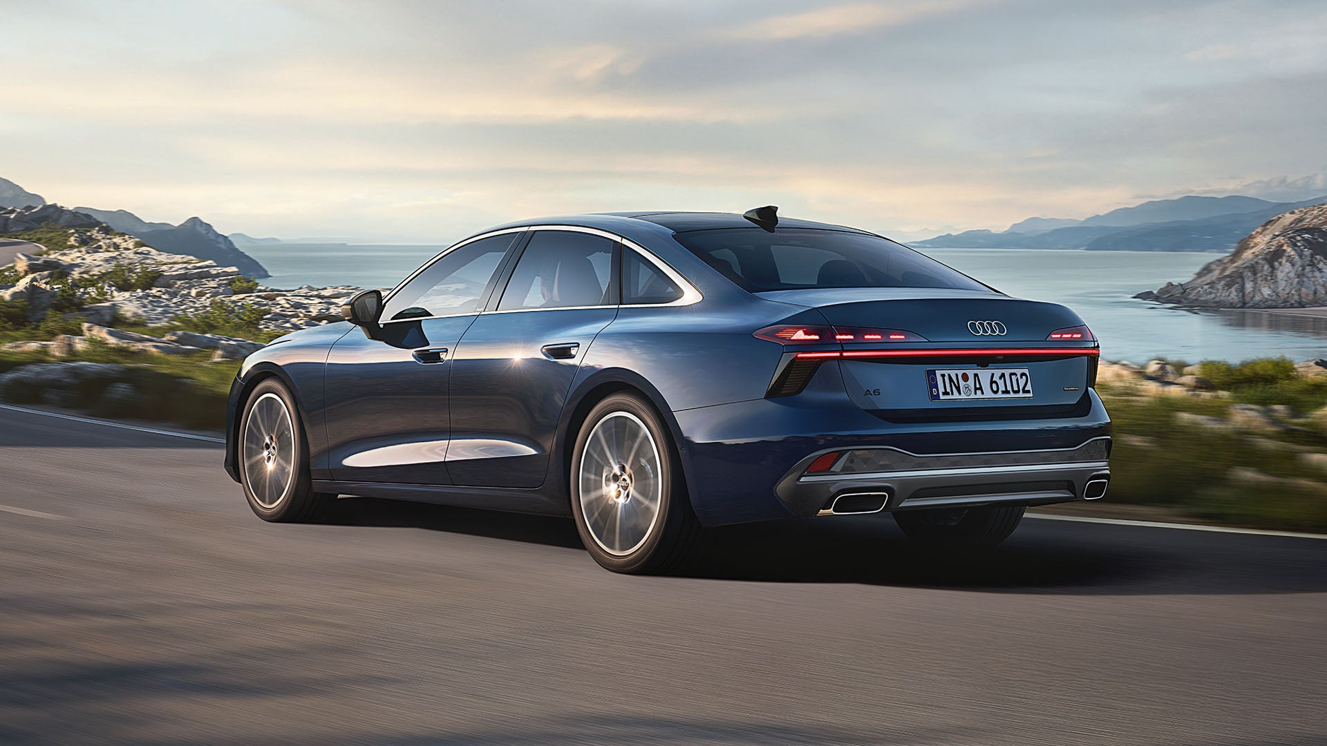 Ein Audi A6 fährt auf einer Straße durch eine felsige Landschaft.