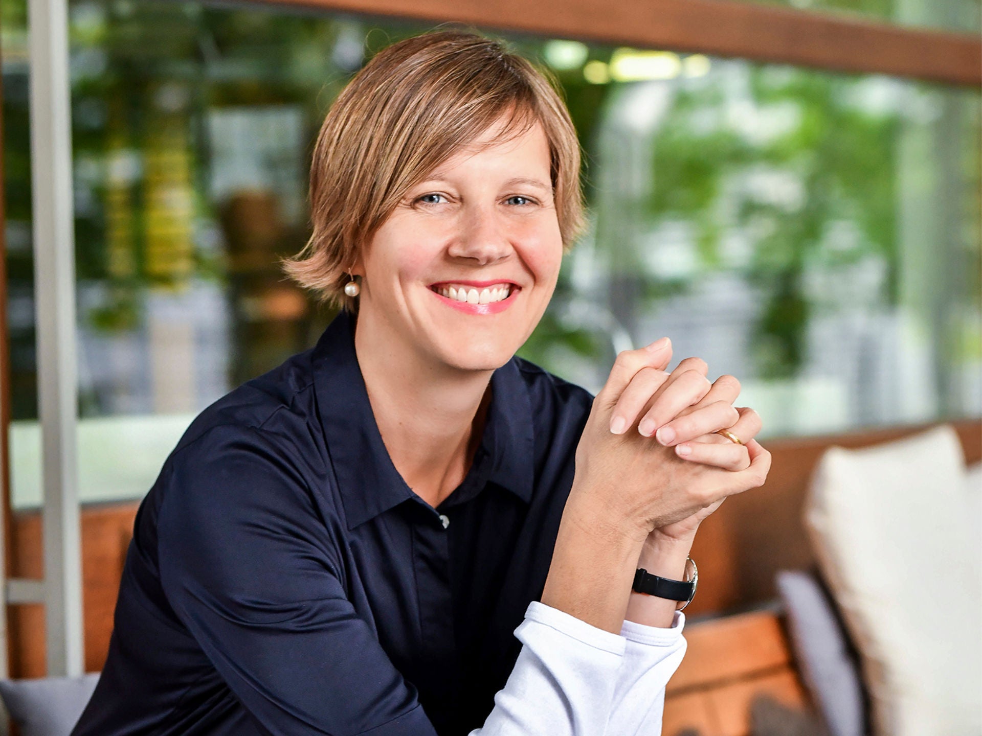 Porträt einer Frau (Antonia Wadé) in dunkler Bluse, die lächelnd die Hände verschränkt.