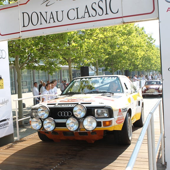 Old timer underneath a sign with "Donau Classic" written on it.