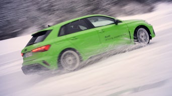Hellgrüner Audi RS 3 Sportback wirbelt beim Driften im Schnee Wasser und Schnee auf.