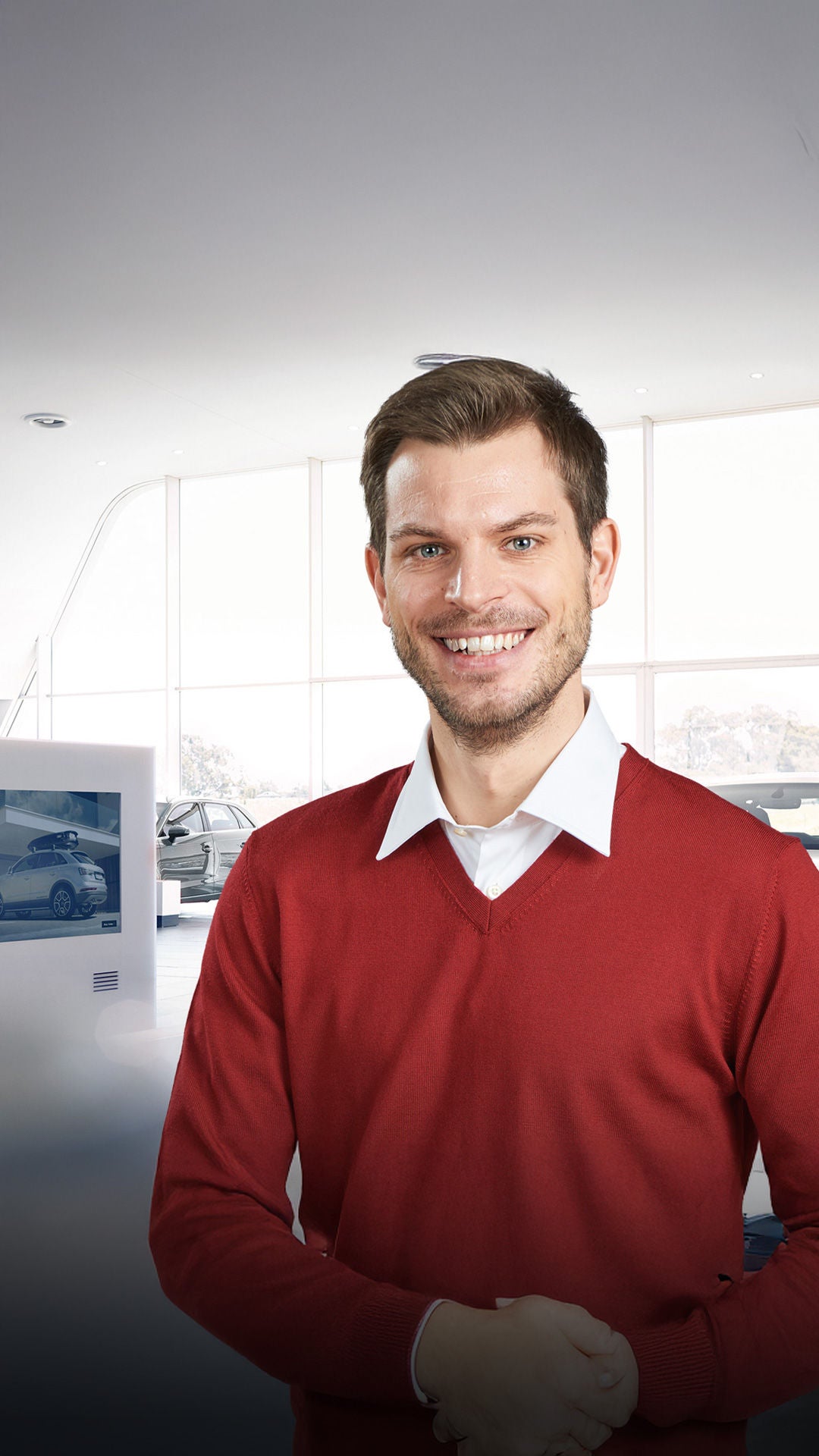 Mann lächelt im Autohaus in die Kamera