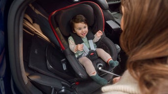 Ein Baby im Kindersitz in einem Audi darunter die Audi Kindersitzunterlage.