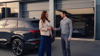 A young woman sitting in an Audi vehicle in an Audi showroom