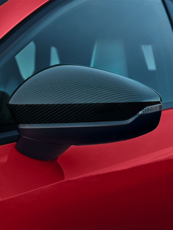 Nahaufnahme eines Außenspiegels mit Carbon-Optik an einer roten Audi A3 Limousine.