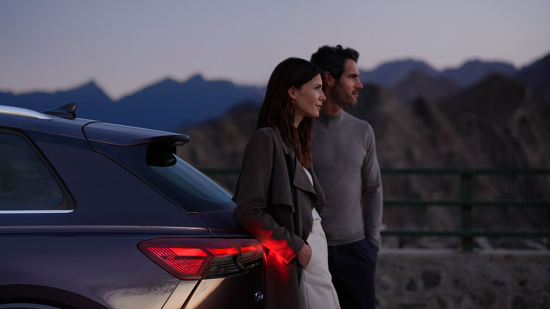 Eine Frau und ein Mann stehen hinter Audi Q4 e-tron