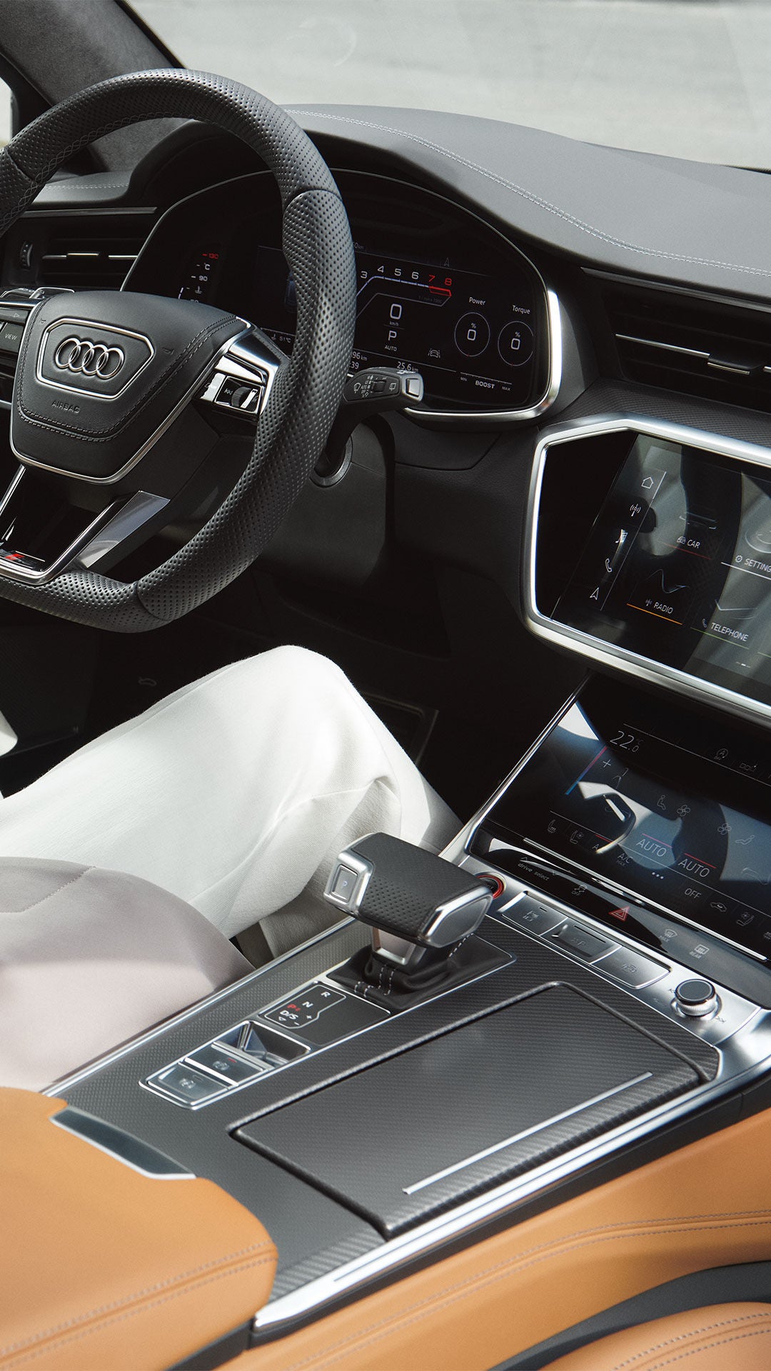 Dunkelhaarige Frau im hellen Business-Outfit im Audi RS 6 Avant, hält Sonnenbrille, Blick auf Lenkrad, Mittelkonsole und Cockpit.