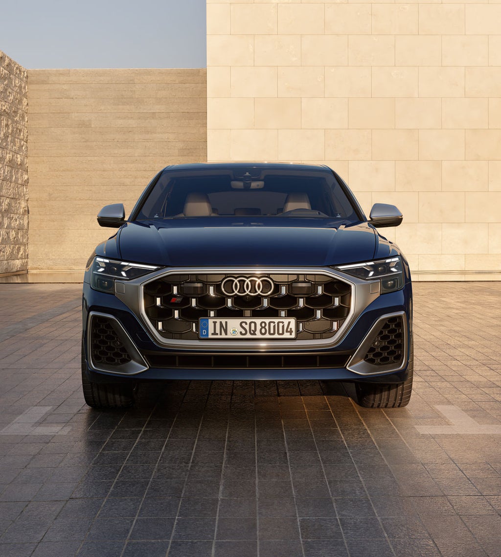 Frontansicht des SQ8 SUV auf einem Parkplatz, umrahmt von hohen Mauern.